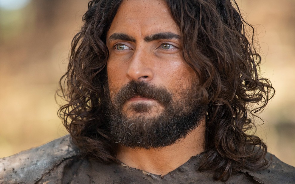 O ator Carlo Porto com cabelos longos e barba desgrenhada como Adão em cena de Gênesis