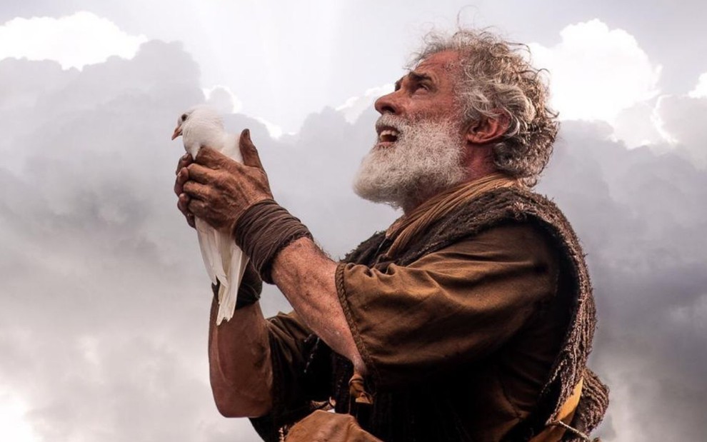 Noé, interpretado por Oscar Magrini, olha para o céu enquanto segura uma pomba
