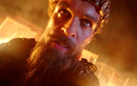 Felipe Roque em cena de Gênesis: em close, rei está em cenário com fogo e tem olhar perdido