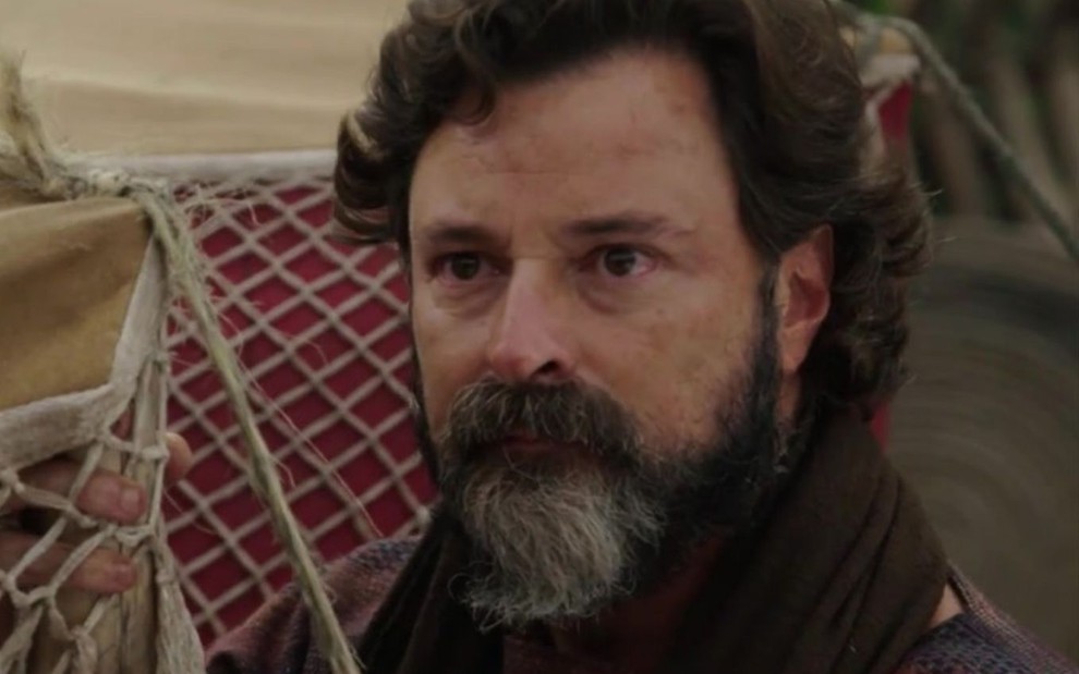 Emilio Orciollo Neto em cena de Gênesis: caracterizado como Ló, ator olha com desconfiança para alguém fora do quadro