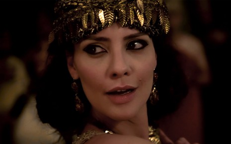 Camila Rodrigues em cena de Gênesis: caracterizada como Nadi, personagem usa adorno dourado na cabeça, maquiagem pesada ao redor dos olhos e olha com desejo alguém fora do quadro