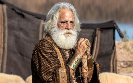 Julio Braga em cena de Gênesis: caracterizado como Terá, personagem está no deserto e olha para o horizonte enquanto segura cajado com as duas mãos