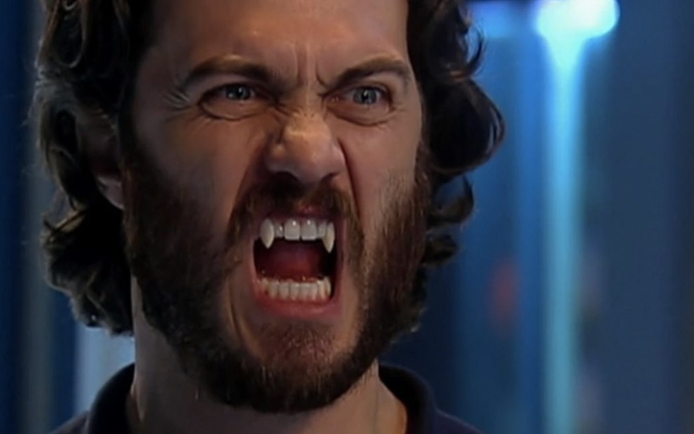 O ator Gabriel Braga Nunes com cabelos e barba grandes, caninos afiados, como um vampiro em cena de Os Mutantes