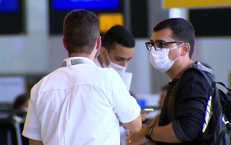 Homens usando máscaras cirúrgicas em imagem de reportagem do Jornal da Record sobre coronavírus