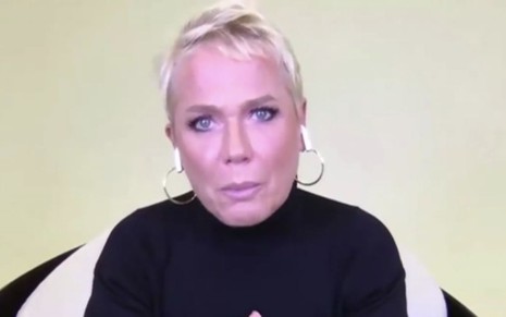 Xuxa Meneguel om expressão séria, de blusa preta, em transmissão da final do reality The Four