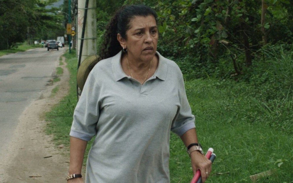 Regina Casé como a Madá, de Três Verões: ela está caminhando na beira de uma estrada