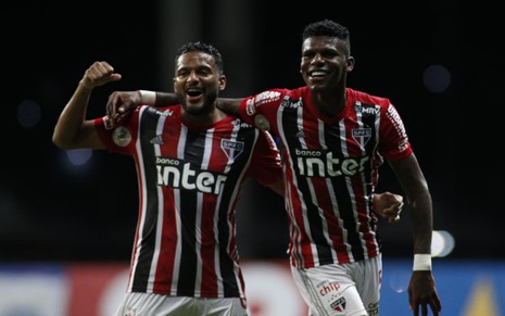 Reinaldo e Arboleda comeram gol do São Paulo, virados para gente, jogadores se abraçam, vestidos com o uniforme do time nas cores vermelho, preto e branco.
