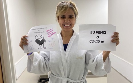 Mulher de Carlos Alberto de Nóbrega no hospital segurando um papel com a frase 'eu venci a Covid-19'