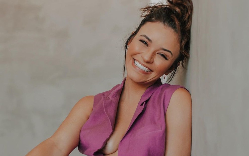 A atriz Talita Younan sorrindo, com uma blusa rosa