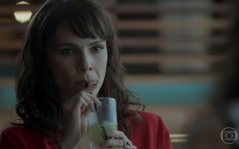 Débora Falabella bebe um suco de canudinho em cena de A Força do Querer