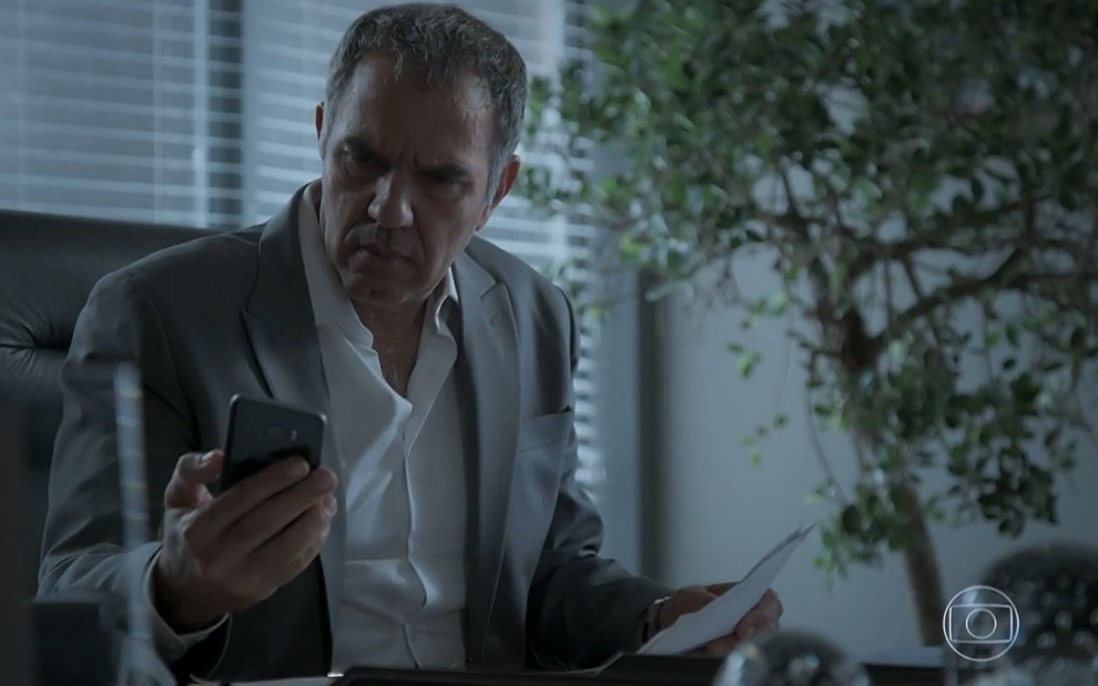 Eurico (Humberto Martins) olha sério para o celular em cena de A Força do Querer