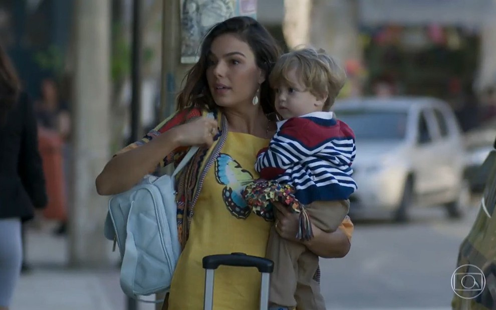 Ritinha (Isis Valverde) na rua com o bebê no colo em cena de A Força do Querer