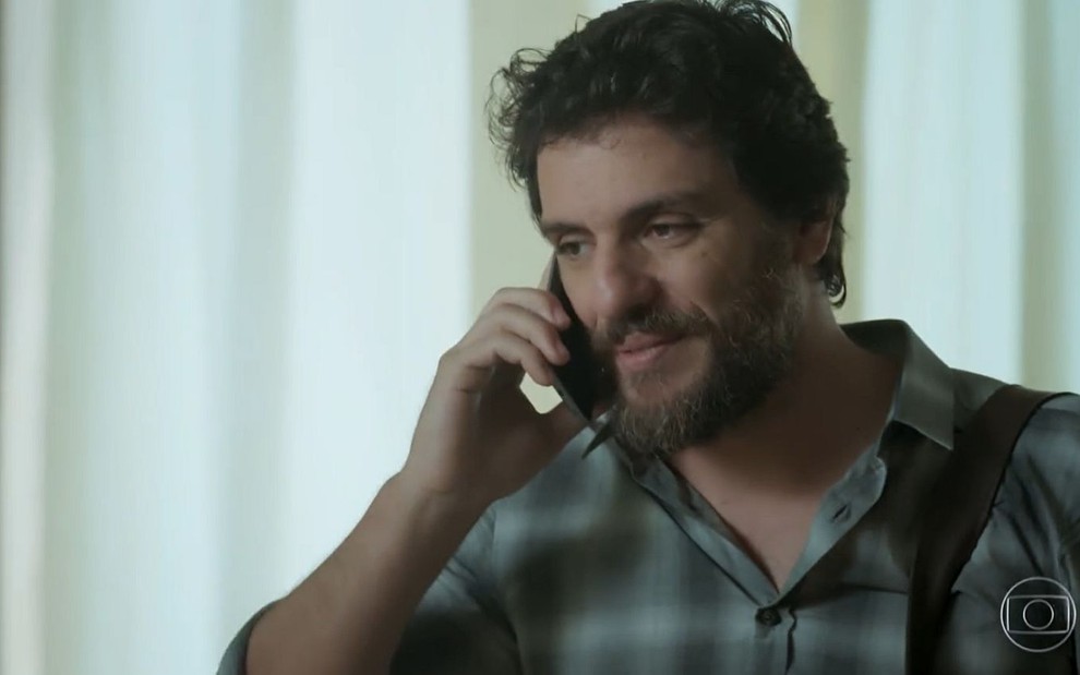 Caio (Rodrigo Lombardi) fala ao telefone com uma camisa xadrez em cena de A Força do Querer
