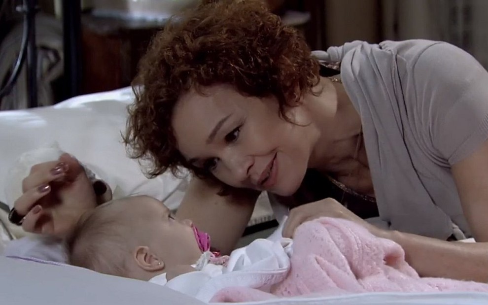 Esther (Julia Lemmertz) deitada na cama com uma bebê em cena de Fina Estampa