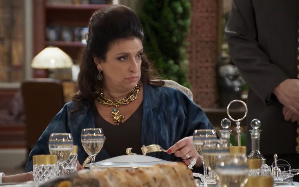 Teodora (Grace Gianoukas) sentada à mesa de jantar em cena de Haja Coração