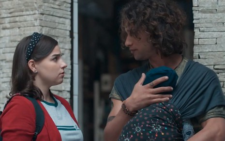 Keyla (Gabriela Medvedovski) olha para Deco (Pablo Morais), que carrega um bebê no sling tipo wrap em cena de Malhação