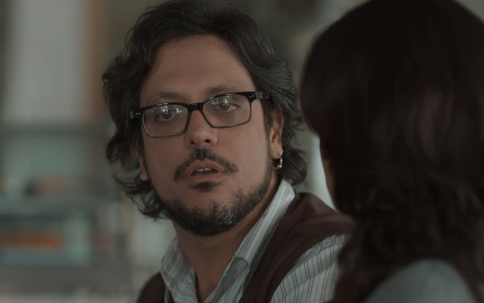 Roney (Lucio Mauro Filho) com cara de desconfiado em conversa com uma mulher em cena de Malhação