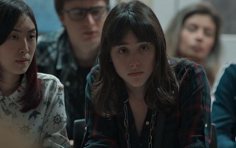 Lica (Manoela Aliperti) sentada em uma reunião ao lado de Tina (Ana Hikari) em cena de Malhação - Viva a Diferença