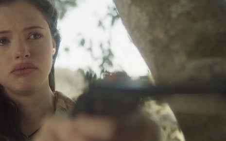 Domitila (Agatha Moreira) com uma arma apontada e chorando em cena de Novo Mundo