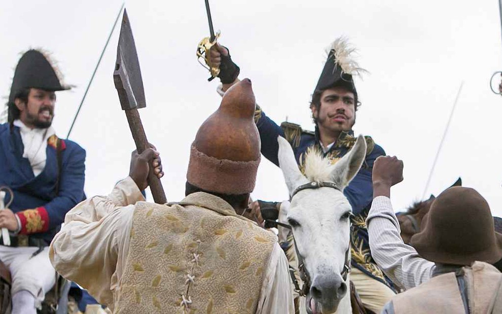 Dom Pedro (Caio Castro) empunha sua espada montado no cavalo cercado pelo seu exército em cena de Novo Mundo