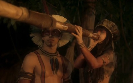Piatã (Rodrigo Simas) ao lado de Jacira (Giullia Buscacio) tocando uma espécie de berrante indígena em Novo Mundo