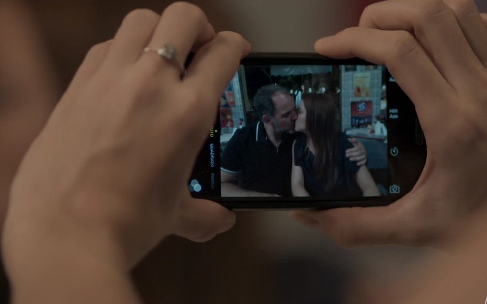 Imagem de uma foto do celular na mão de Sofia (Priscila Steinman) em que Germano (Humberto Martins) e Lili (Vivianne Pasmanter) se beijam em Totalmente Demais