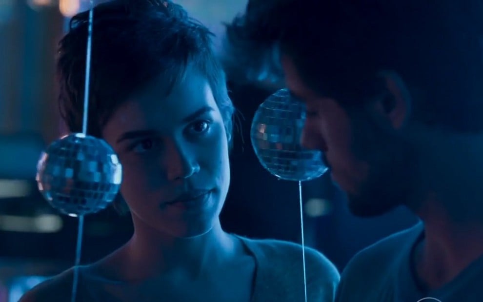 Leila (Carla Salle) conversa com Jonatas (Felipe Simas) em uma boate de luz azul em cena de Totalmente Demais