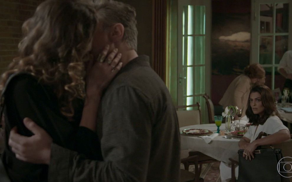 Carolina (Juliana Paes) assiste ao beijo de Arthur (Fabio Assunção) e Natasha (Lavinia Vlasak) sentada em uma mesa de restaurante em cena de Totalmente Demais