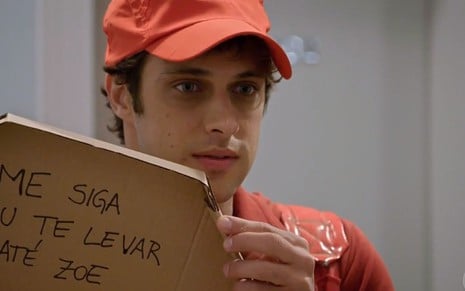 Guto (Ronny Kriwat) disfarçado de entregador de pizza com um recado escrito na caixa em cena de Apocalipse