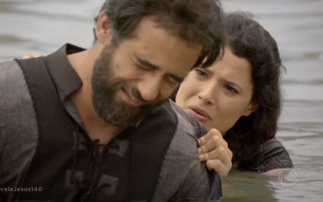 Simão Fariseu (Rafael Sardão) chora dentro de um lago consolado por Laila (Manuela do Monte) em cena de Jesus
