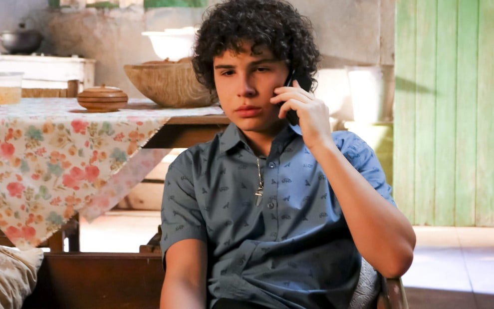 João (igor Jansen) fala no celular em cena de As Aventuras de Poliana