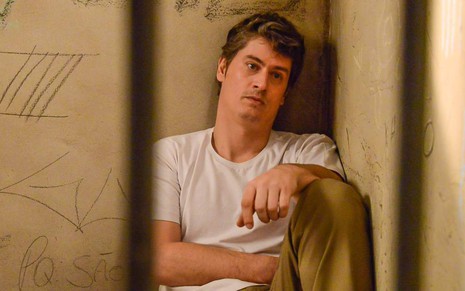 Waldisney (Pedro Lemos) sentado no chão na cadeia em cena de As Aventuras de Poliana