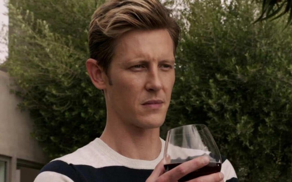 Com cabelo curto e cara de sério, Gabriel Mann segura uma taça de vinho em imagem da série Revenge