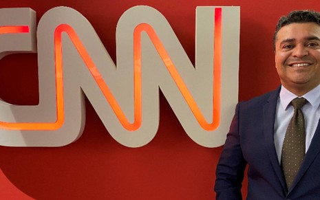 Sorridente, o novo contratado da CNN Brasil, Roberto Nonato, aparece ao lado do logo do canal