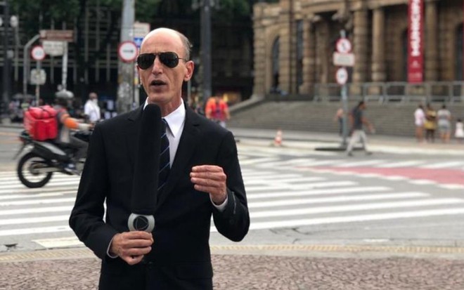 Rodolfo de terno preto, óculos escuros e com o tradicional microfone gigante na mão