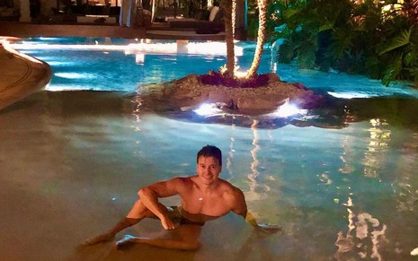 Rodrigo Faro de sunga sentado dentro da piscina da sua casa, que imita uma ilha particular