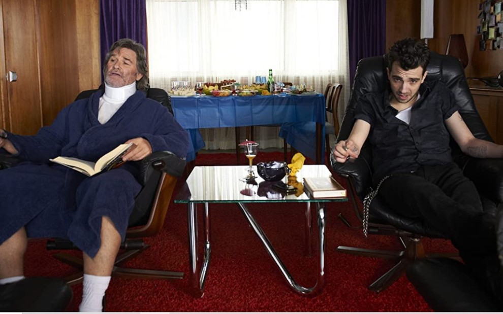 Kurt Russell com uma proteção no pescoço e Jay Baruchel sentados em cadeiras em cena do filme Roubar É uma Arte