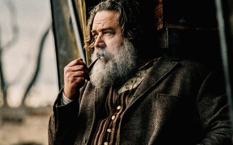 Russell Crowe fuma um cachimbo em cena do filme A Verdadeira História de Ned Kelly
