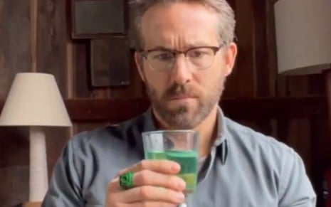 Ryan Reynolds aparece tomando bebida verde e usando o anel de Lanter Verde enquanto assiste a uma cena do film