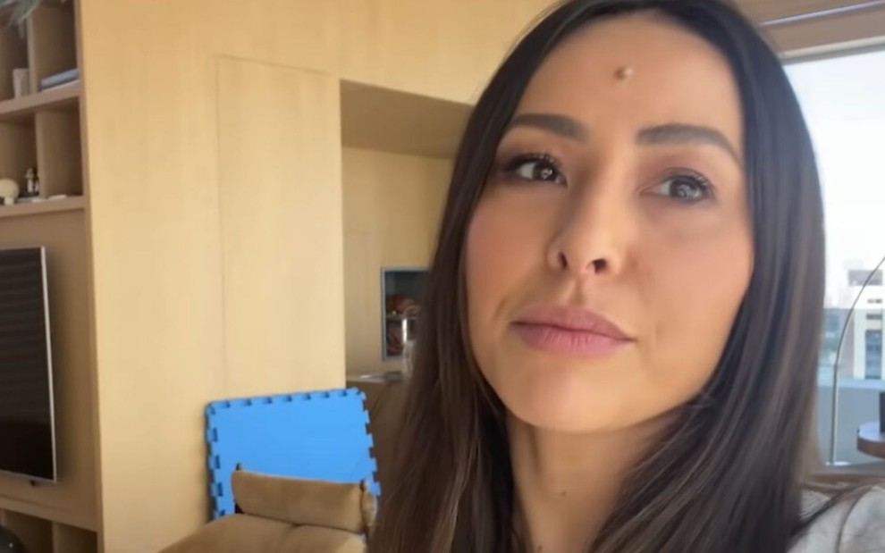 Na sala de sua casa, Sabrina Sato grava vídeo com o celular