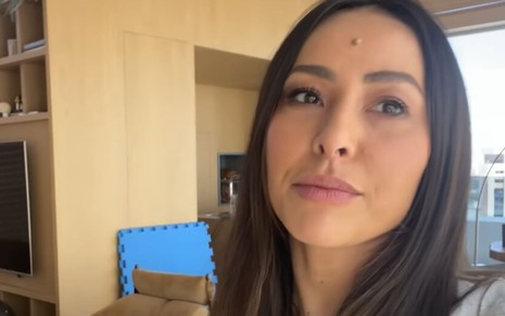 Na sala de sua casa, Sabrina Sato grava vídeo com o celular