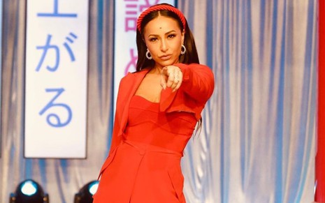 Sabrina Sato com um vestido vermelho, fazendo bico e apontando com o dedo para a frente