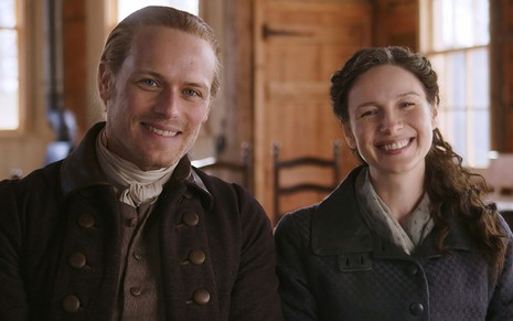 Sam Heughan e Caitriona Balfe, caracterizados como Jamie e Claire, sorriem nos bastidores da sexta temporada de Outlander