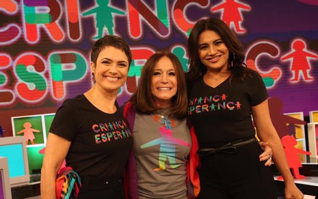 Sandra Annenberg, Susana Vieira e Dira Paes abraçadas usando camisetas do Criança Esperança, no estúdio da Globo