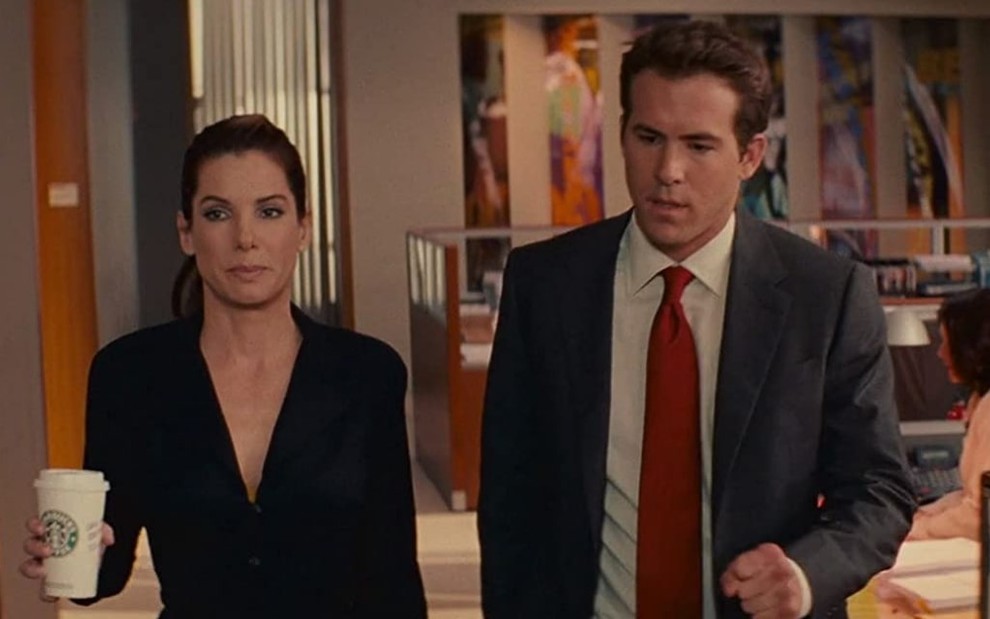 Em um escritório, Sandra Bullock e Ryan Reynolds conversam em cena do filme A Proposta (2009)