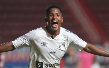 O jogador Ângelo Gabriel corre sorrindo no campo de braços abertos em comemoração ao gol do Santos