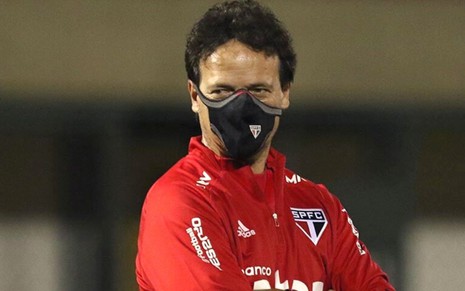 De máscara, o técnico Fernando Diniz observa o São Paulo com os braços cruzados na beira do gramado
