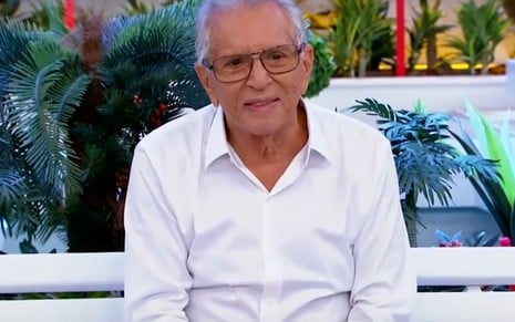 O apresentador do SBT Carlos Alberto de Nóbrega sentado no banco de A Praça É Nossa