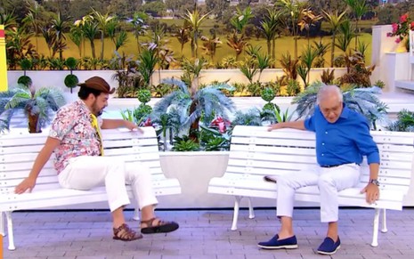 Matheus Ceará e Carlos Alberto de Nóbrega no cenário de A Praça É Nossa adaptado com dois bancos, cada um está sentado em um