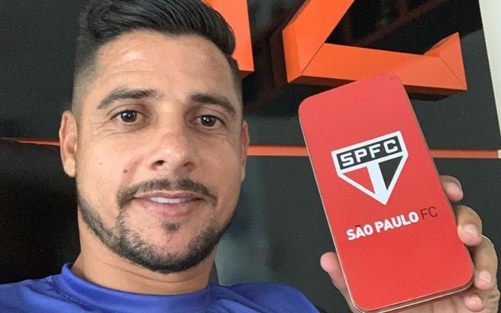 O ex-jogador Cicinho posa para foto e mostra capinha de celular do São Paulo
